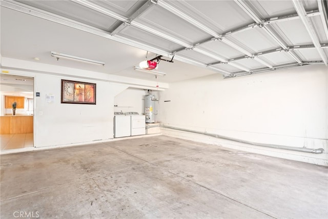 garage with water heater, washing machine and dryer, and a garage door opener