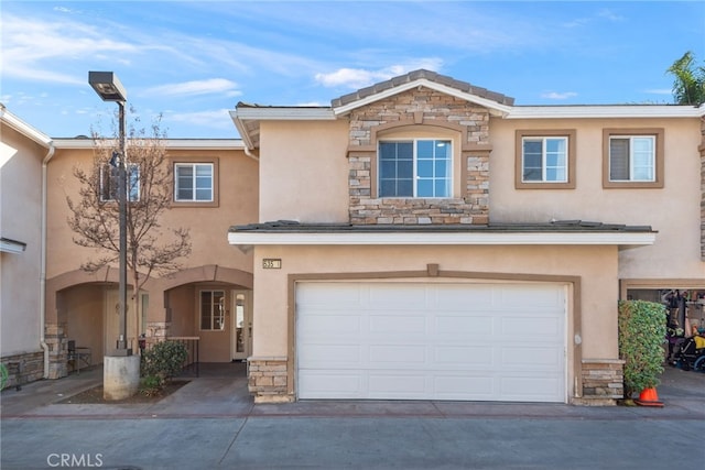 view of front of home with a garage, stone siding, concrete driveway, and stucco siding