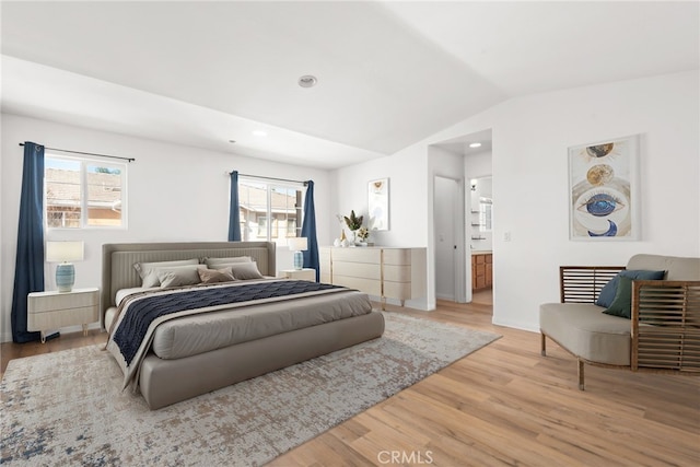 bedroom featuring lofted ceiling, multiple windows, wood finished floors, and baseboards