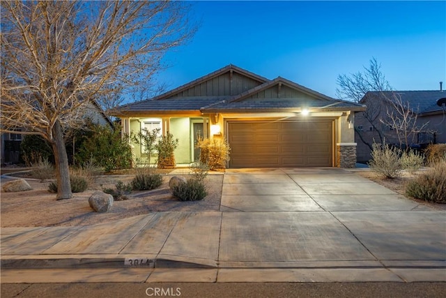 craftsman house with a garage, driveway, stone siding, and stucco siding