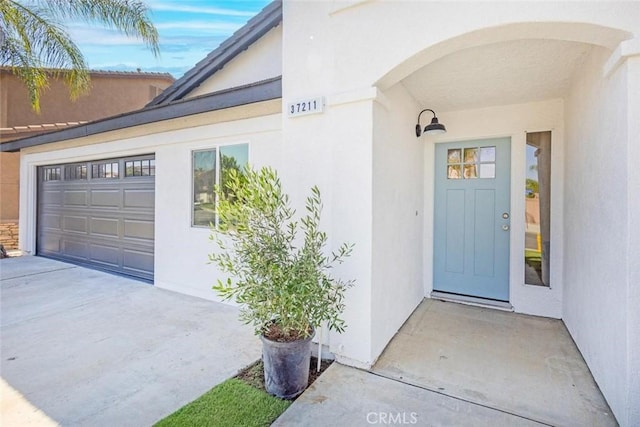 doorway to property with a garage and stucco siding