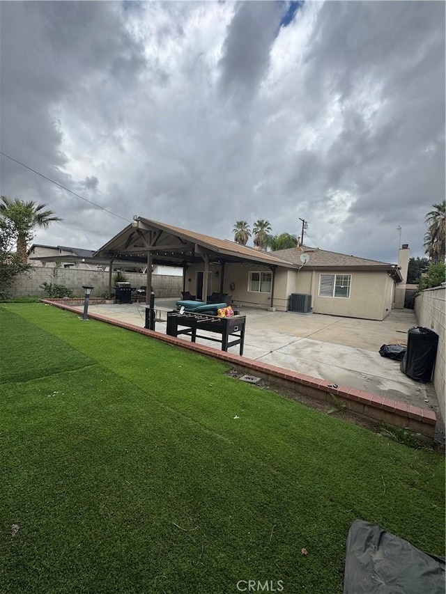 back of house with a patio, central air condition unit, fence, a yard, and stucco siding