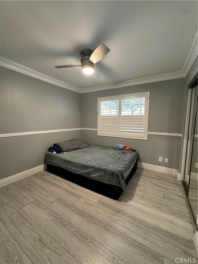 bedroom featuring ornamental molding, a ceiling fan, baseboards, and wood finished floors