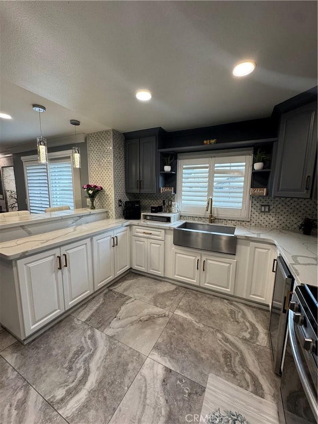 kitchen with stove, open shelves, a sink, and decorative light fixtures