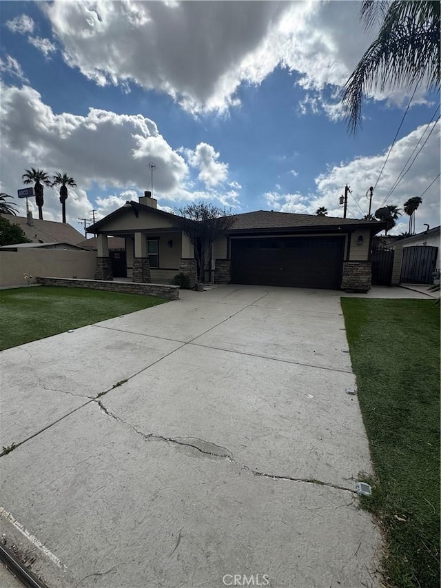 view of front of property with a garage, concrete driveway, stone siding, fence, and a front yard