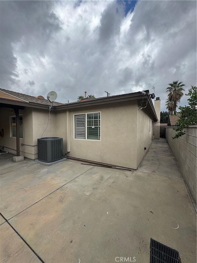 back of property with cooling unit, a patio area, fence, and stucco siding