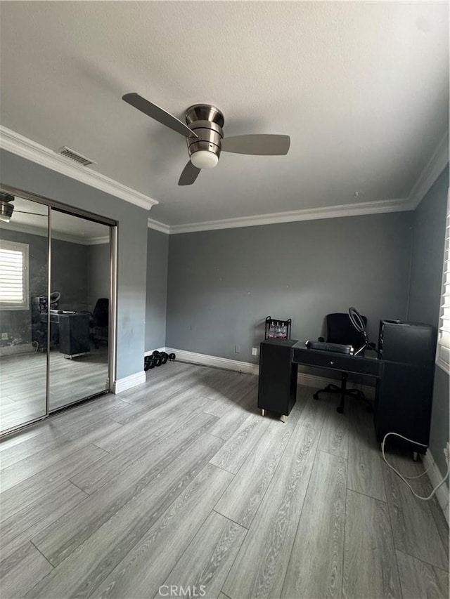 office space featuring baseboards, visible vents, ceiling fan, wood finished floors, and crown molding