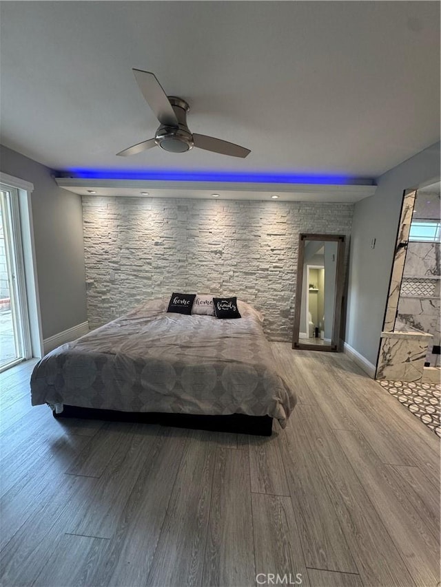 bedroom with a ceiling fan, multiple windows, baseboards, and wood finished floors