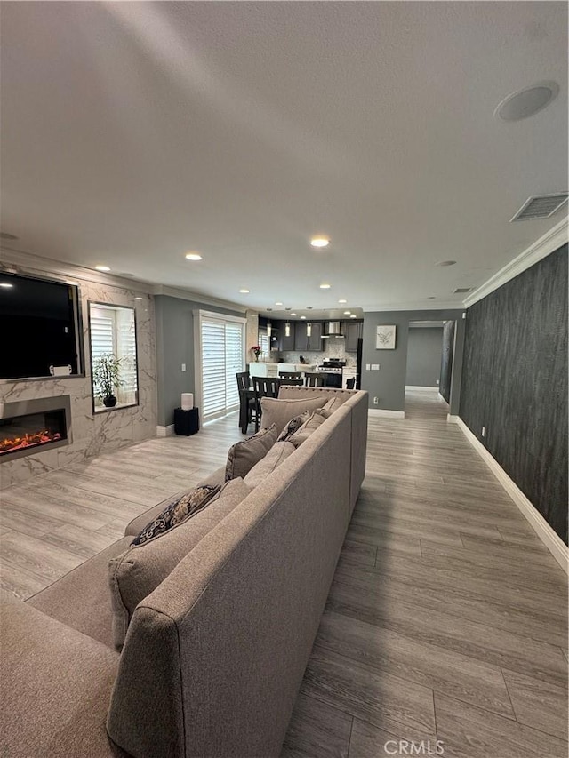 living room with baseboards, visible vents, a premium fireplace, wood finished floors, and recessed lighting