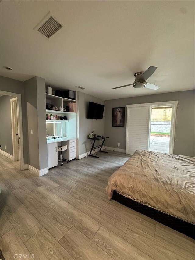 unfurnished bedroom with baseboards, visible vents, built in desk, and wood finished floors