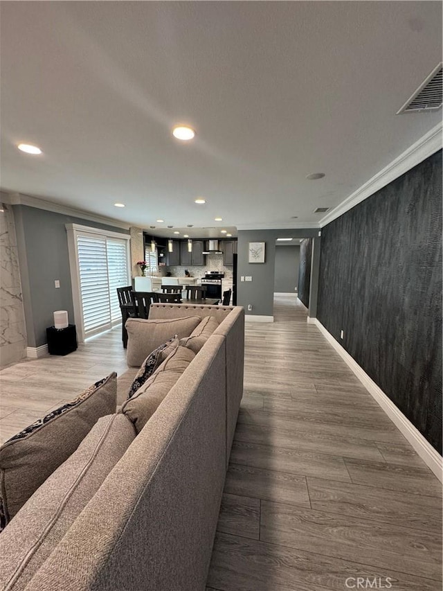 living room with recessed lighting, visible vents, crown molding, and wood finished floors