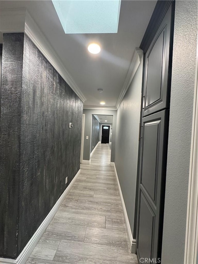 corridor with light wood finished floors, baseboards, and crown molding