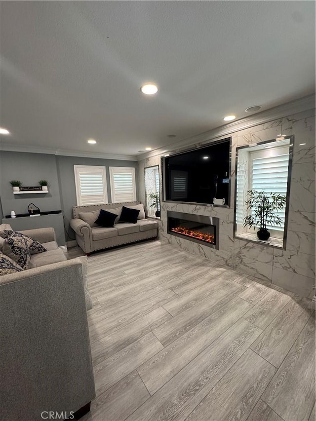 living area featuring a high end fireplace, a wealth of natural light, crown molding, and wood finished floors