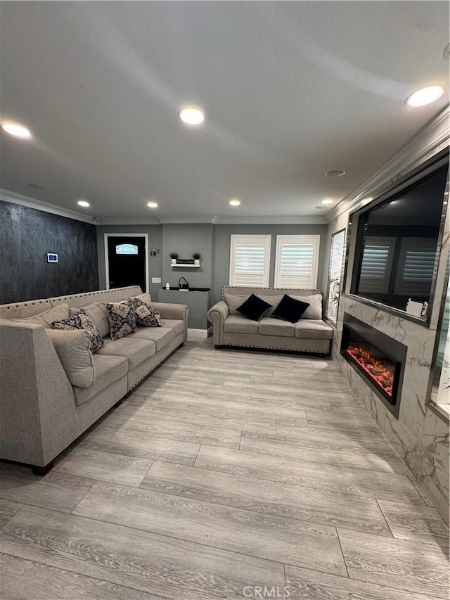 living area with light wood-type flooring, a premium fireplace, recessed lighting, and crown molding