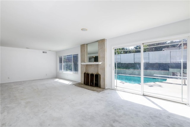 unfurnished living room with carpet floors, visible vents, and a healthy amount of sunlight