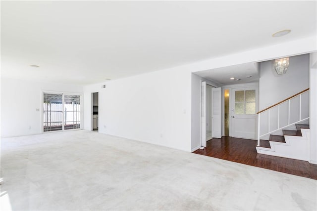 unfurnished room with carpet flooring, stairway, and an inviting chandelier