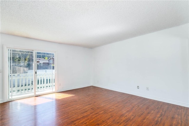 unfurnished room with a textured ceiling, wood finished floors, and baseboards