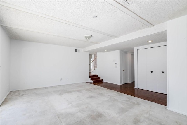 unfurnished room featuring carpet floors, visible vents, a textured ceiling, baseboards, and stairs