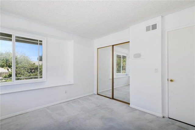 unfurnished bedroom featuring carpet floors, a closet, visible vents, a textured ceiling, and baseboards