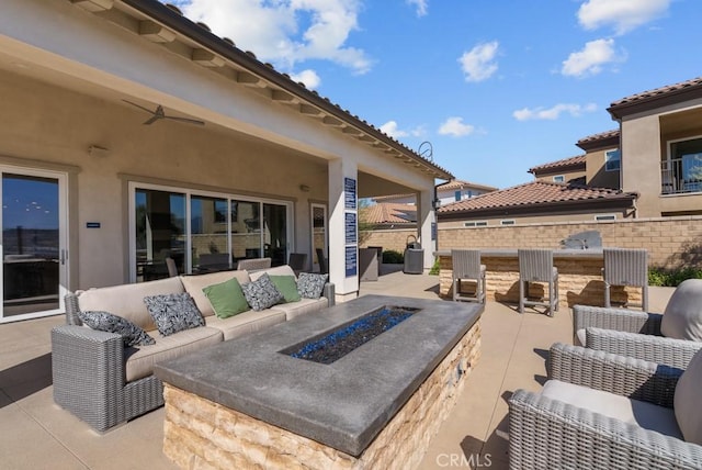 view of patio / terrace with outdoor dry bar, a ceiling fan, an outdoor living space with a fire pit, and fence