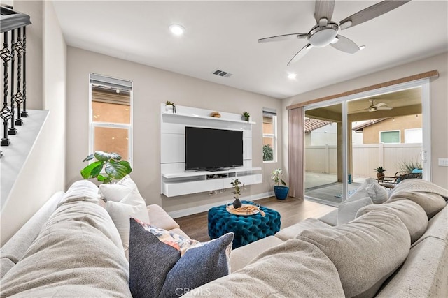 living room featuring wood finished floors, visible vents, a wealth of natural light, and ceiling fan