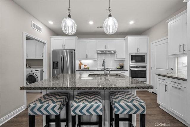 kitchen featuring a sink, stainless steel appliances, backsplash, under cabinet range hood, and visible vents