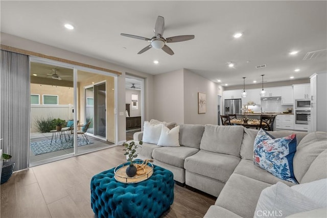 living area with a ceiling fan, wood finished floors, and visible vents