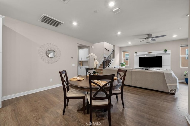 dining space with stairway, visible vents, dark wood-type flooring, baseboards, and ceiling fan
