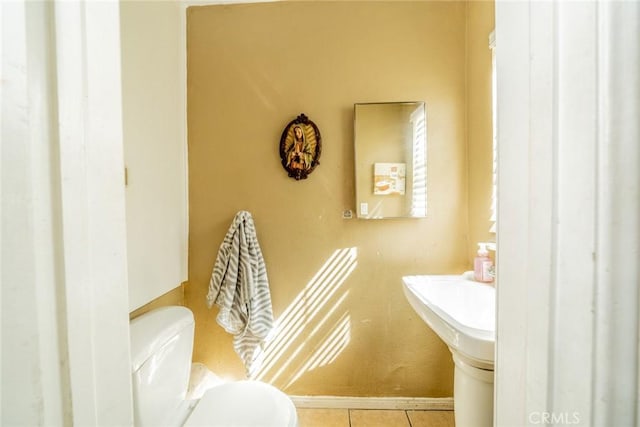 half bathroom featuring toilet, tile patterned flooring, and baseboards