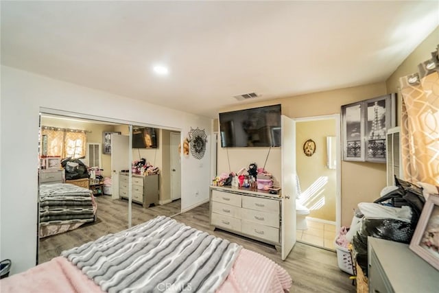 bedroom featuring a closet, visible vents, connected bathroom, and light wood-style flooring