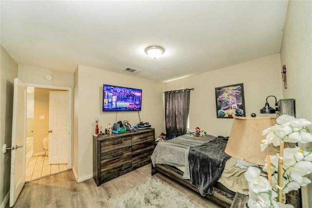 bedroom featuring visible vents, baseboards, and wood finished floors