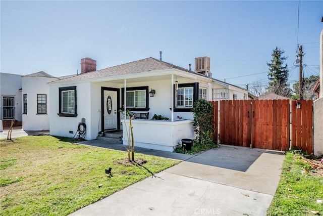 view of front of property featuring fence, a chimney, a front lawn, and stucco siding