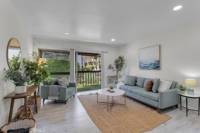 living room featuring a wall mounted AC, light wood-type flooring, and recessed lighting