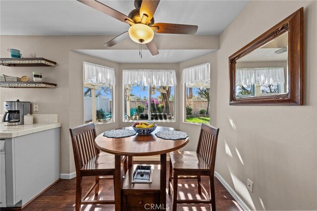 dining space featuring dark wood-style floors, baseboards, and a ceiling fan