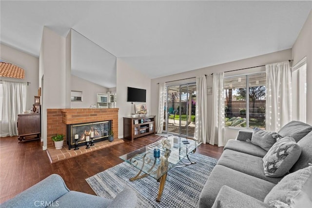 living area with vaulted ceiling, a fireplace, and wood finished floors