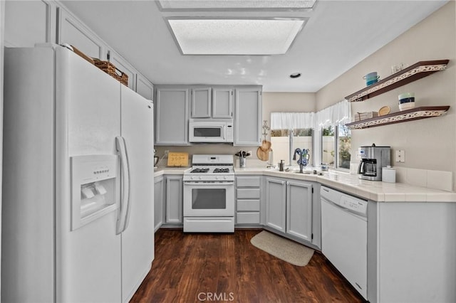 kitchen featuring white appliances, dark wood finished floors, tile countertops, open shelves, and a sink