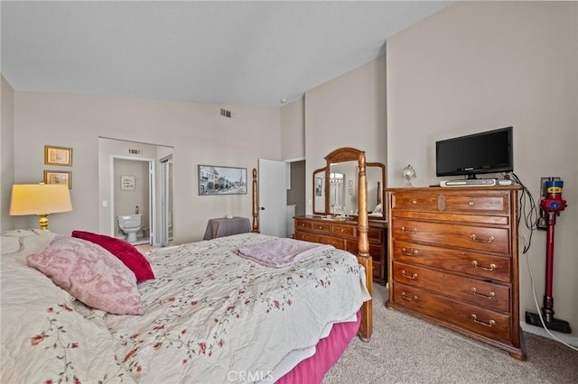 bedroom with lofted ceiling, light carpet, visible vents, and ensuite bathroom