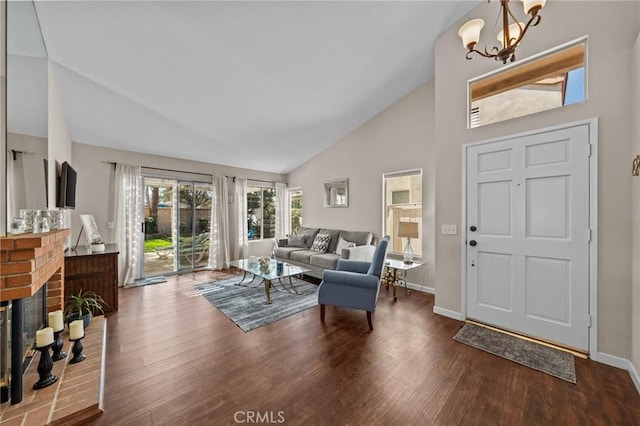 living room featuring dark wood-style floors, a fireplace, high vaulted ceiling, and an inviting chandelier