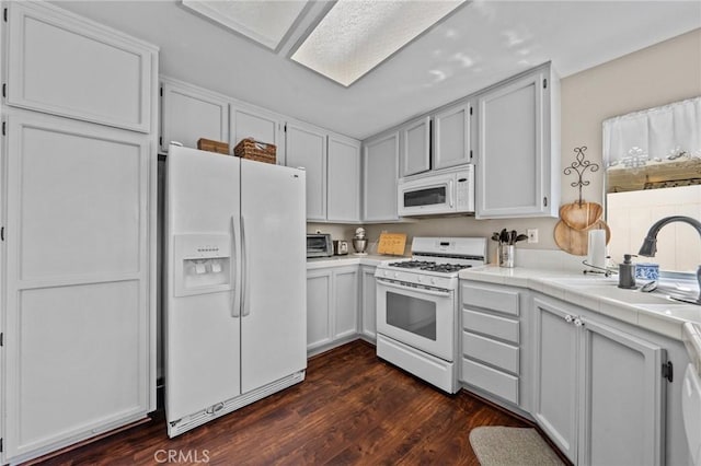 kitchen featuring dark wood finished floors, tile countertops, white cabinetry, a sink, and white appliances