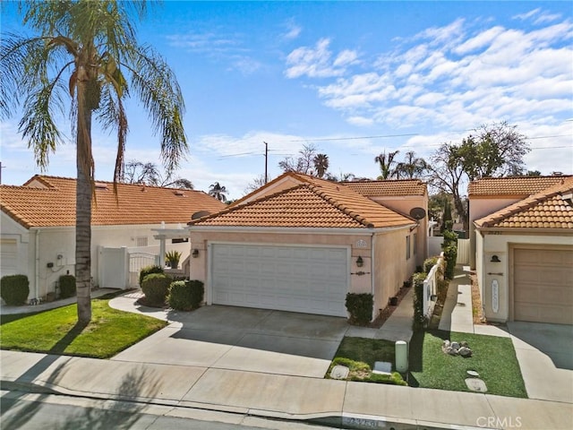 mediterranean / spanish-style home with concrete driveway, an attached garage, fence, and stucco siding