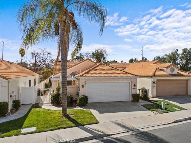 mediterranean / spanish house featuring an attached garage, a tile roof, a gate, and stucco siding