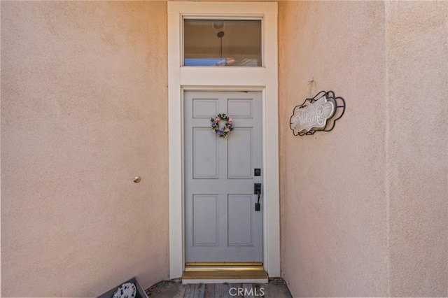 doorway to property featuring stucco siding