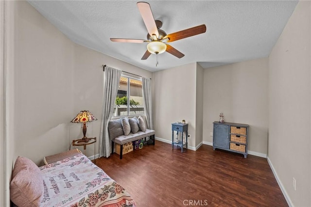 living area with ceiling fan, a textured ceiling, baseboards, and wood finished floors