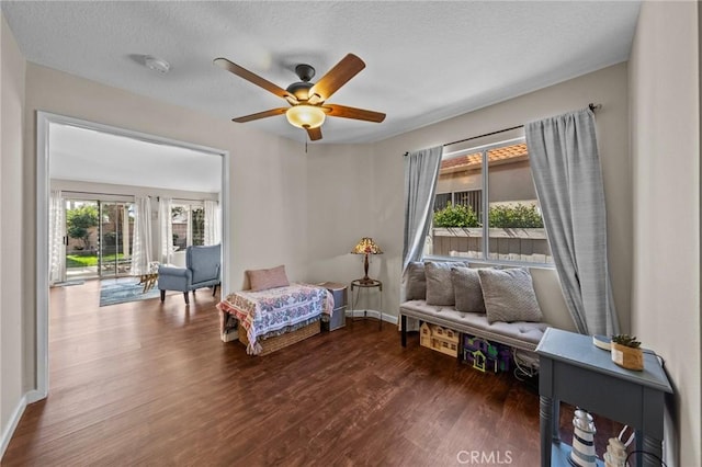 sitting room with ceiling fan, a textured ceiling, baseboards, and wood finished floors