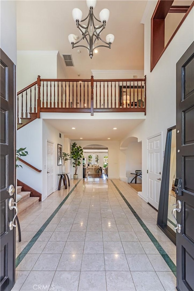 foyer with visible vents, a notable chandelier, stairway, and a high ceiling