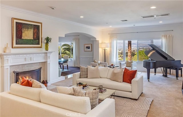 living area with ornamental molding, arched walkways, visible vents, and light carpet