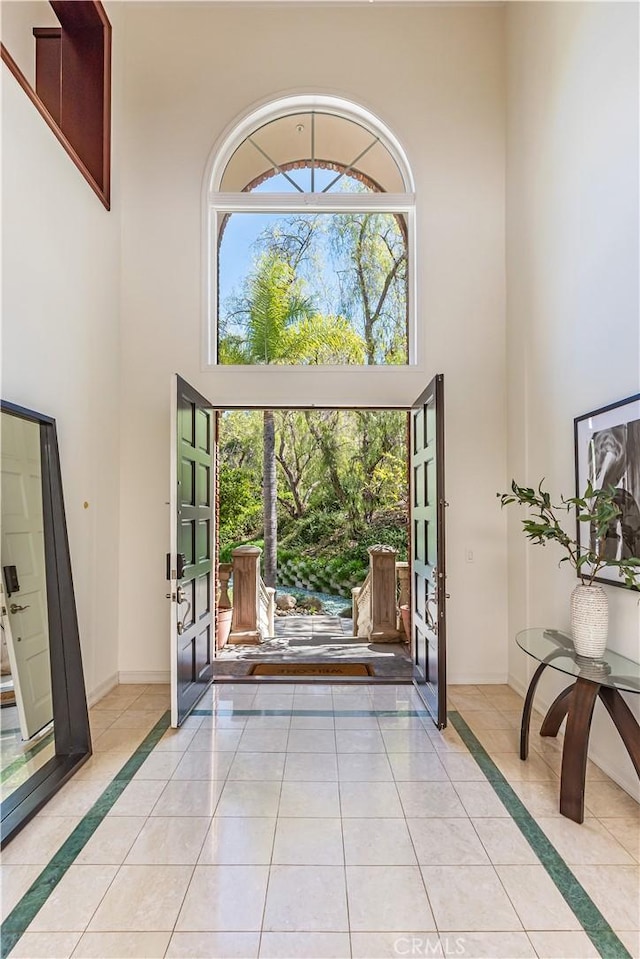 entryway featuring a high ceiling, light tile patterned flooring, and baseboards