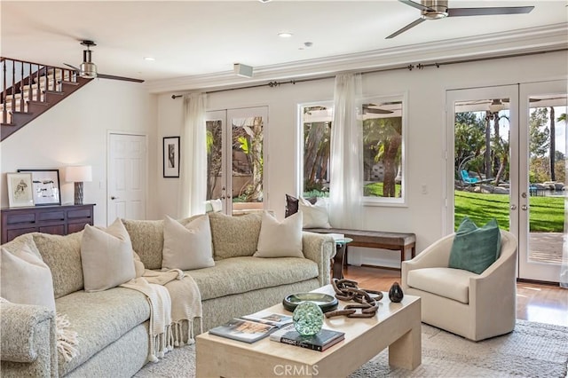 living room with ornamental molding, french doors, light wood-type flooring, and a ceiling fan