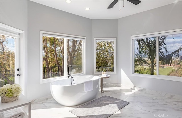 bathroom featuring a soaking tub, marble finish floor, plenty of natural light, and recessed lighting