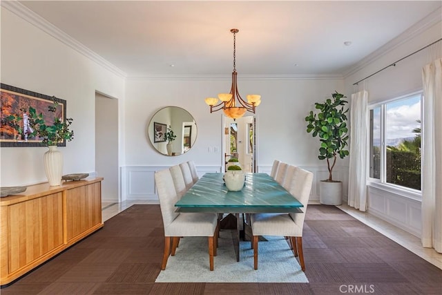 dining area featuring ornamental molding, a wainscoted wall, a notable chandelier, and a decorative wall